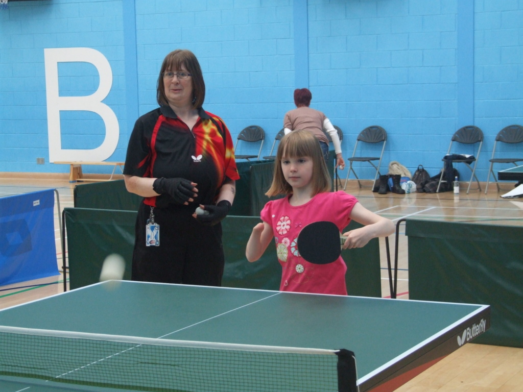 Young girl playing table tennis with coach