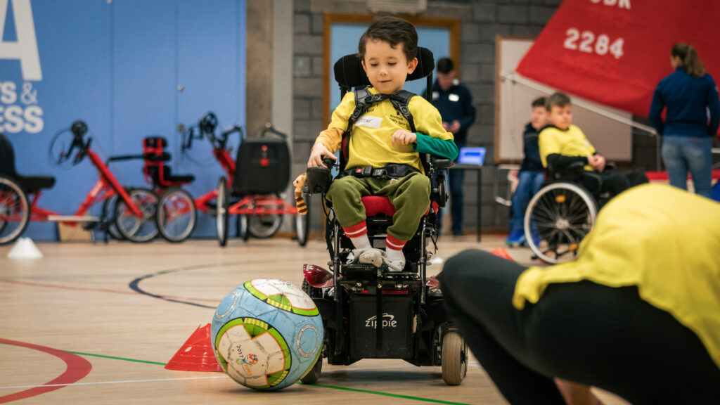 Photo of a young boy in a power wheelchair playing power football.